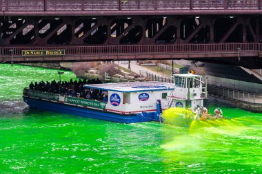 Chicago, IL - 11 Mart 2023: Paslı turuncu boyalı yeşil suyla kaplı 130 yerel tesisatçı sendikası yıllık St. Paddy Günü etkinliği sırasında bir sahil gezisi teknesinden yeşil su püskürttü.
