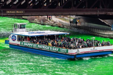 Chicago, IL - 11 Mart 2023: Bir Shoreline Manzara mavnası müşterilerle dolu ve Kelt bandosu açık yeşil nehirde yıllık St. Patrick Günü etkinliği sırasında yeni boyanmış..