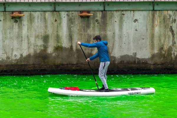 シカゴ 2023年3月11日 毎年恒例の聖パトリックの日イベント中に 新しく染められた緑の川をスタンドアップパドルボードを漕ぐ男 — ストック写真