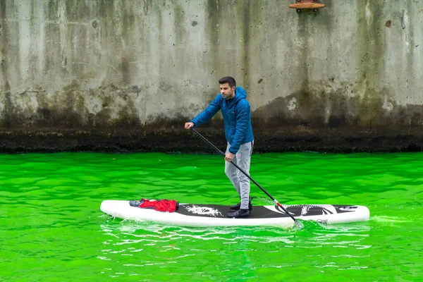 シカゴ 2023年3月11日 毎年恒例の聖パトリックの日イベント中に 新しく染められた緑の川をスタンドアップパドルボードを漕ぐ男 — ストック写真