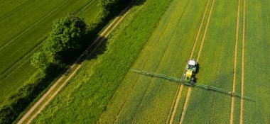 Alanı spreyleyen bir traktörün hava görüntüsü. İnsansız hava aracı bakış açısından tarımda kimya. Modern tarım geçmişi kavramı.