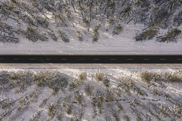 stock image Aerial drone view of road in idyllic winter landscape at sunset. Street running through the nature from a birds eye view