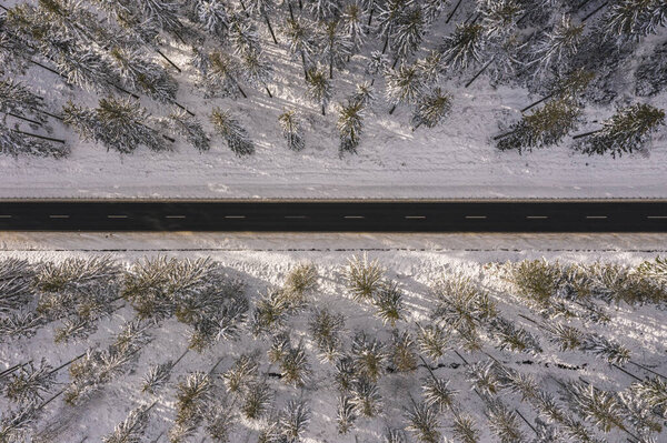 Aerial drone view of road in idyllic winter landscape at sunset. Street running through the nature from a birds eye view