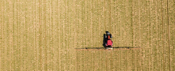 stock image Aerial image of tractor spraying soil and young crop in springtime in field