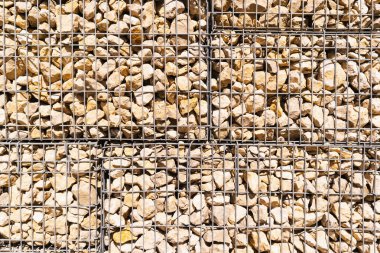 Metalik ağ içinde taş duvar 