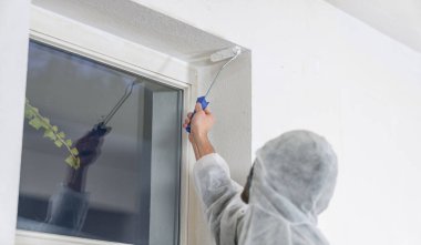 Boyacı, bir odanın köşesini beyaz renge boyamak için boya silindiriyle çalışıyor. Bunu kendin yap konsept görüntü