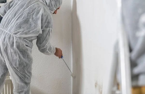 Close up of painter working with paint roller to paint the room in white color. do it yourself concept image
