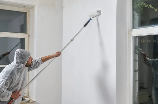 painter working with paint roller to paint the wall of a room. do it yourself concept image