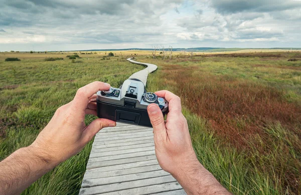 Man Hand Hålla Vintage Kamera Mot Ett Landskap Med Strandpromenad — Stockfoto