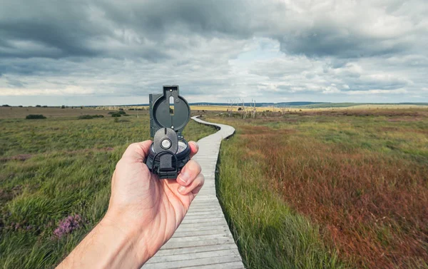 Male Traveler Holds Compass Background Bog Landscape Wooden Trail Cloudy — Stock Photo, Image