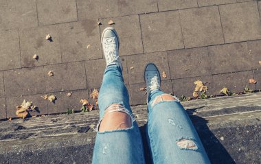 Genç bir kadın duvarda oturuyor ve ayaklarını sallıyor, yukarıdan gelen kişisel bir dokunuş..