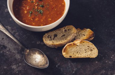 Fesleğenli domates çorbası ve siyah arka planda seramik kasede baget. Sağlıklı yeme kavramı 