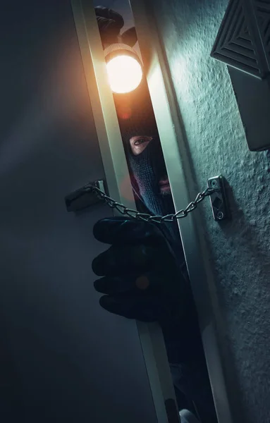 stock image burglar with torch entering a door with chain at night