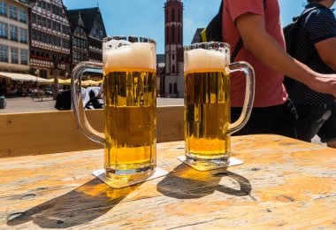 Two mugs of beer on table at Frankfurt in germany clipart