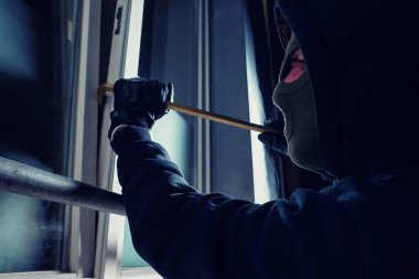 burglar using crowbar to break into a victim's house at night  clipart