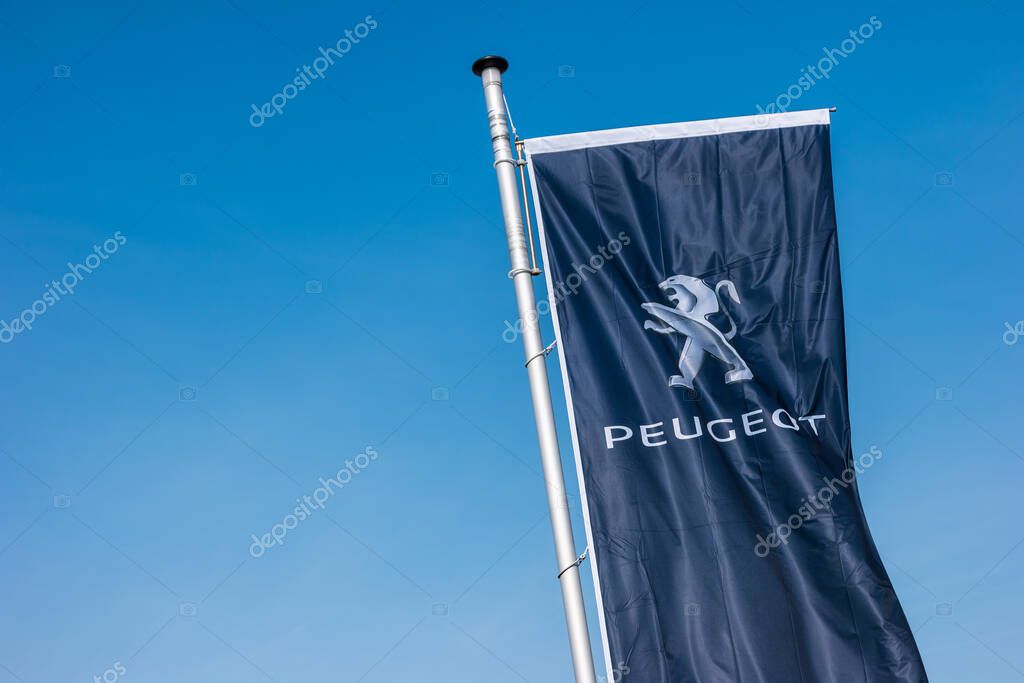 AACHEN, GERMANY MARCH, 2017: Peugeot logo on a flag against blue sky. Peugeot is a French cars brand, part of PSA Peugeot Citroen.