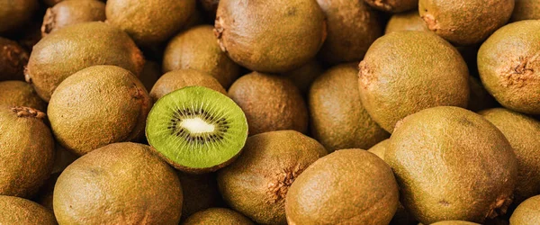 Lots of kiwi fruits with halved kiwi in a pile, vegan food