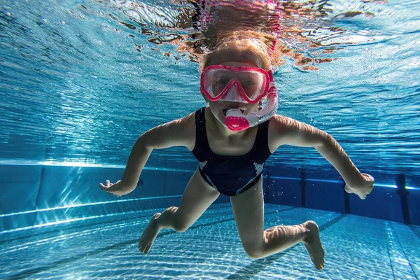 child wearing diving mask swimming in the pool, underwater shot