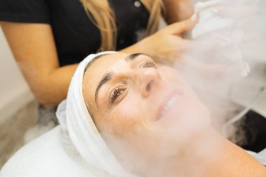 Kozmetik salonunda yüz derisine ozon buharlı güzellik tedavisi, buharla yüzleşen kadınlar. Yumuşak cilt için buhar