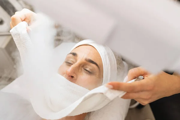 Beauty treatment of face with ozone facial steamer in beauty center or cosmetology salon.
