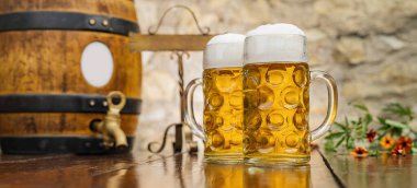 Masada köpük ve ahşap varilli iki kupa bira duruyor. Oktoberfest, Münih, Almanya