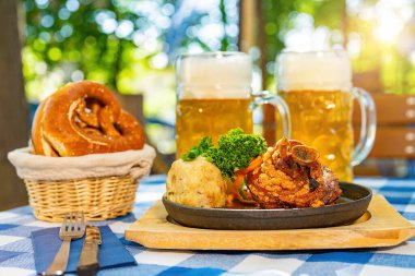 Schweinshaxe, geleneksel Bavyera mutfağı kızarmış jambon (domuz budu) ve bira bahçesindeki bir masada patates köftesi, bira bardağı.