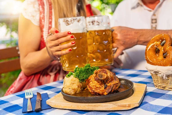Bayerisches Paar Klappert Bierkrüge Mit Traditioneller Bayerischer Küche Mit Schweinshaxe — Stockfoto