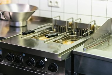 Patates kızartması pişirmek. Patatesler endüstriyel fritözde pişirilir. Kızgın yağda kızartılmış ürünler. Fast food restoranı. Garnitür. Endüstriyel fritöz 