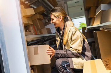 Bir müşteriye teslim etmek için minibüs paketlerinde arama yapan bir teslimatçı.