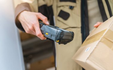 Vardiyası sırasında barkod tarayıcıyla barkod taraması yapan bir teslimatçı. Kurye Taşıma konsept görüntüsü
