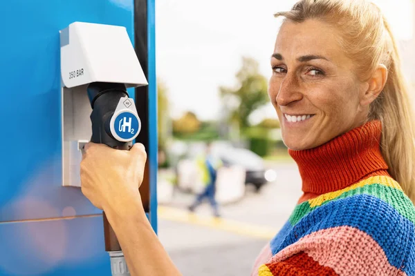 Schöne Frau Lächelnd Hält Eine Zapfsäule Mit Wasserstofflogo Der Tankstelle — Stockfoto