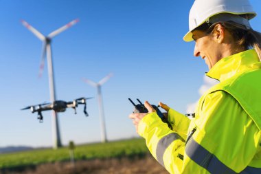 Female Operator inspecting Wind turbine with drone. Drone inspection of a renewable energy wind park concept image clipart