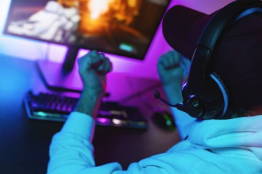 Oyuncu, Kişisel Bilgisayarında Birinci Şahıs Shooter Online Video Oyunu 'nda oynamaktan ve kazanmaktan mutlu. Oda Işığı Yazan: Neon Lights Retro Arcade Stili.
