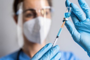 Kadın doktor, Aşı Merkezi 'nde ayarlanan bir şişe Moderna Covid-19 aşısından bir doz gösteriyor.