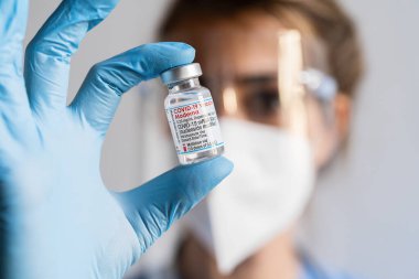 BERLİN, ALMANLIK 10 ARALIK 2021: Bir kadın doktor aşı merkezinde ayarlanan bir şişe Moderna Covid-19 aşısından bir doz alır.