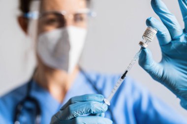 BERLİN, ALMANLIK 10 ARALIK 2021: Bir sağlık çalışanı aşı merkezinde düzenlenen bir şişe Pfizer-BioNTech aşısından bir doz alır.