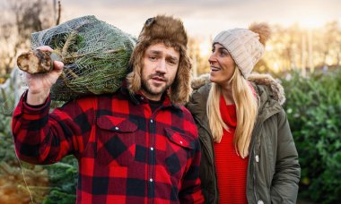 Noel ağacı almak isteyen ve seçtiği ağacı işaret eden bir adam.