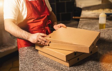 Pizza fırıncısı İtalyan pizzacıya pizza götürmek için bir kutuda pizza paketliyor.