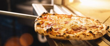 Pizza üreticisi geleneksel restoranda fırından pizza alıyor, pankart boyutunda.