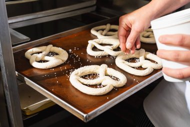 Fırıncı tuzlu krakerleri bir tepside tuzluyor.