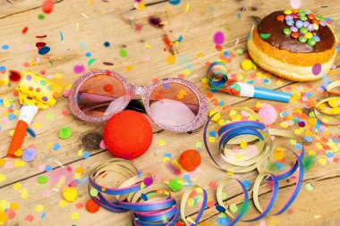 Almanya 'dan gelen karnaval çöreği, üzerinde konfeti, flama ve parti bardakları olan ahşap bir yüzeye çikolata şekeri konmuş. Bir karnaval partisi ya da partiler için arka plan