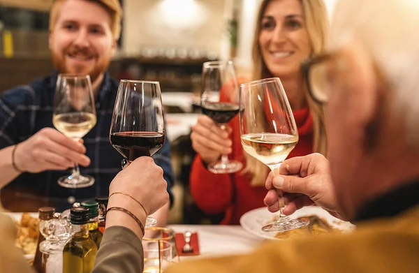 Family drinking and toasting red and white wine at dinner party - Happy drunk people having fun together at italian restaurant winery bar, Dining lifestyle concept image