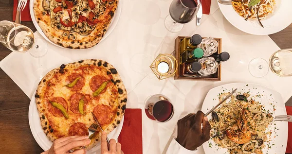 stock image friends eating pasta, pizza and wine - people having meal in restaurant - Focus on center table - Summer lifestyle, food and friendship concept