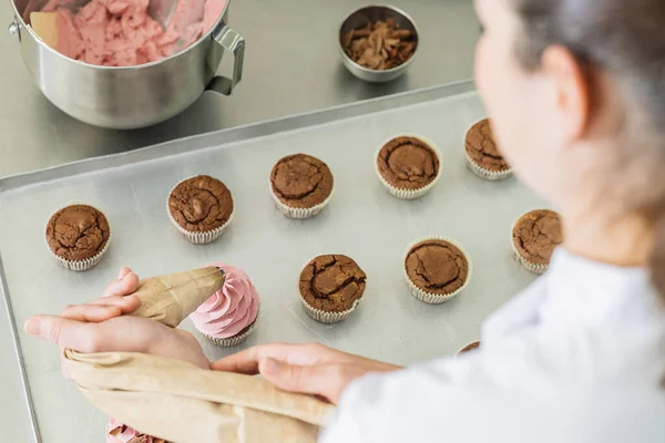 stock image Professional women in pastry bakery as confectioner glazing muffins with icing bag