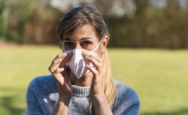 N95 FFP2 kullanan kadın, diğerlerinin Coronavirus COVID-19 ve SARS Cov 2 enfeksiyonlarını önlemek için bir antivirüs koruma maskesi takıyor.. 