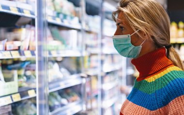Dondurucu bölümündeki süpermarkette bir kadın covid-19 Coronavirus salgınından dolayı virüs önleyici maske takıyor. 