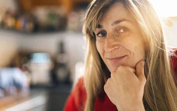 stock image Close up  Woman Standing in the kitchen with Hand on the Chin. Captured her While Looking at the Camera indoors with copy space