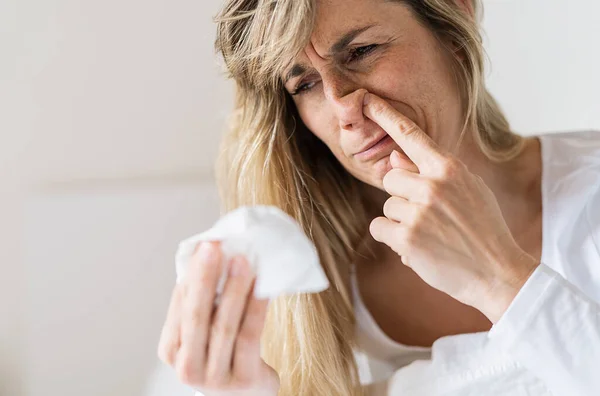 Sick woman Picking his nose. Upset ill european lady sits  in bed, blowing and picks her nose using paper napkin tissue. Cold And Flu Concept