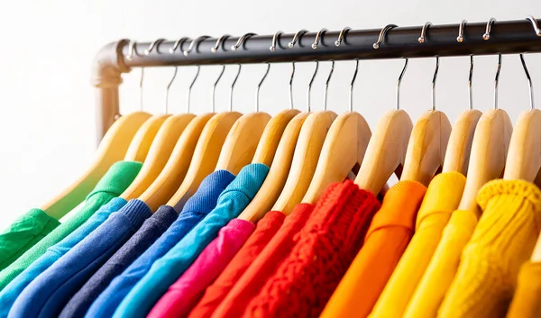 stock image Colors of rainbow LGBT. Variety of casual clothes on wooden hangers