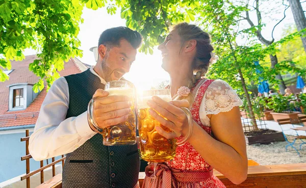 Mutlu çift Bavyera bira bahçesinde ya da oktoberfest 'te Biranın ve güneşin tadını çıkarın